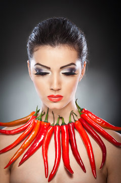 beautiful young woman portrait with red hot and spicy peppers