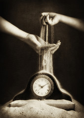 child and adult hand with sand and clock
