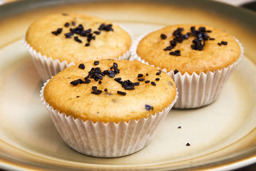 Freshly baked muffins in cups topped with chocolate .