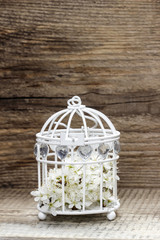 Birdcage with flowers inside on rustic wooden background, copy s