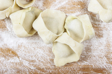 Making dumplings, raw pastry on wooden board.