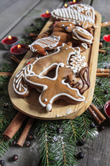 Gingerbread cookies on wooden tray among fir branches and red ca