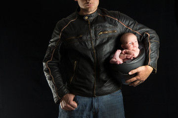 A motorcyclist father holds his newborn baby in his helmet