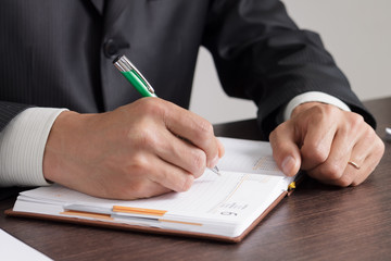 Businessman makes notes to his diary