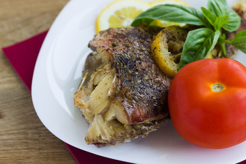 Baked grouper served with lemon and basil on white plate
