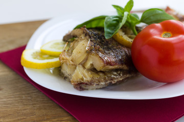 Served grilled fish with lemon and basil with tomato