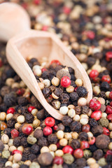 Closeup of mixed peppercorns with wooden spoon