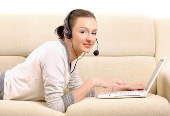 Young woman lying on sofa with laptop