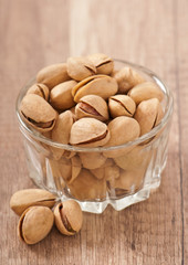 pistachios in a glass bowl on a wooden background