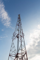 Communications tower against a blue sky with clouds.