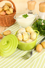 Tender young potatoes with sour cream and herbs in pan