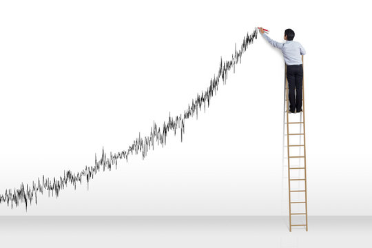 Businessman standing on ladder drawing diagrams and growth graph