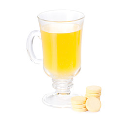 The glass of soluble vitamin C pills lying near