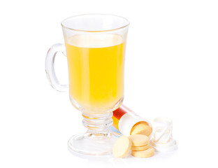 The glass of soluble vitamin C pills lying near