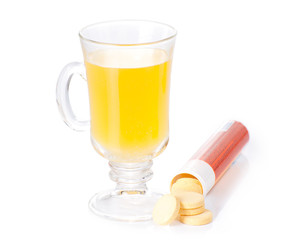 The glass of soluble vitamin C pills lying near