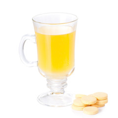 The glass of soluble vitamin C pills lying near