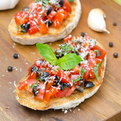 bruschetta with tomato, olives, basil, cheese on a wooden board