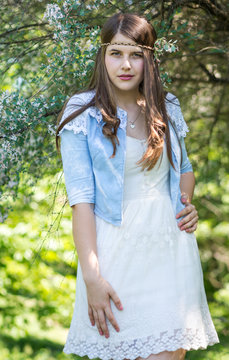 beautiful body of the young woman posing near the green tree