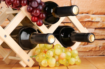 Bottles of wine placed on wooden stand on stone wall background