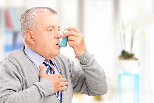 Mature man treating asthma with inhaler