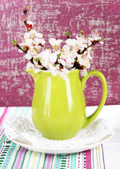 Beautiful blooming branches in pitcher on bright background