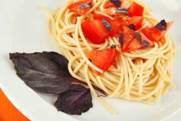 Spaghetti with tomatoes and basil leaves close-up