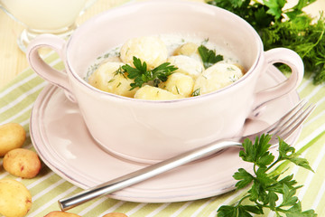 Tender young potatoes with sour cream and herbs in pan