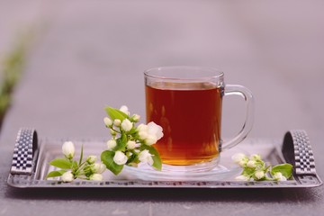 Cup of tea with blooming apple tree branch