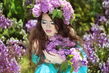 Beautiful young woman in lilac flowers, outdoors portrait