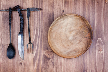 Wooden plate, spoon, fork, knife on wood background