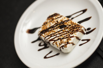 Helado con chocolate en plato de ceramica blanco y cuchara.