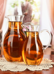 Apple juice in pitchers on table in room