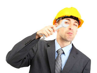 Young businessman in helmet with wrench isolated on white.