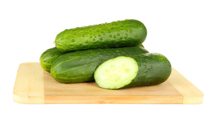 Tasty green cucumbers on wooden cutting board, isolated on