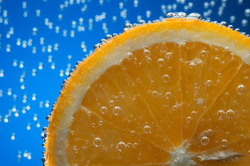 Slice of orange in water with air bubbles