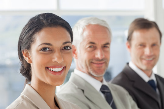 Cheerful businesswoman smiling with colleagues behind