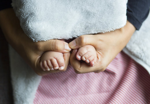 A baby girl's feet being held in the hands of her mother