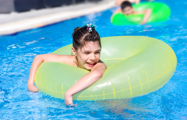 Девочка в надувном круге купается в бассейне
