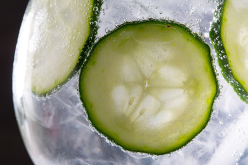 Gin tonic cocktail with cucumber and ice  macro closeup