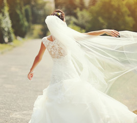 Fototapeta na wymiar happy brunette bride spinning around with veil