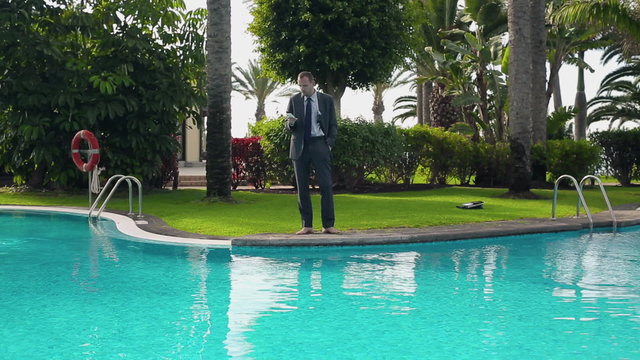 Businessman walking by the poolside with cellphone