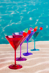 colorful cocktail in a row with cherry on tropical sand beach