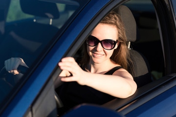 Fototapeta na wymiar Beautiful businesswoman in sunglasses driving in the car