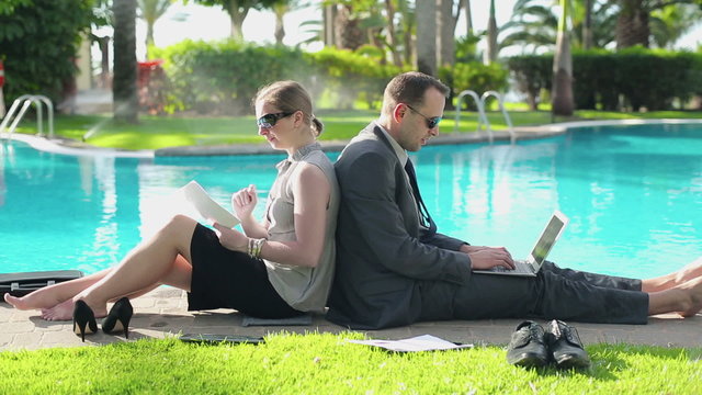Business couple working with together by the swimming-pool