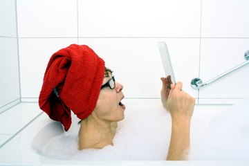 Excited woman in bathtub with tablet computers