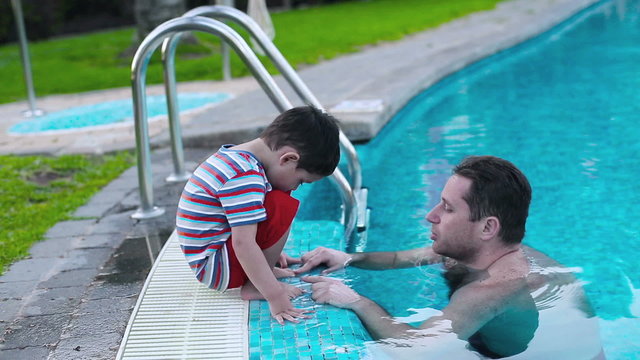 Father talking with his son in the swimming-pool