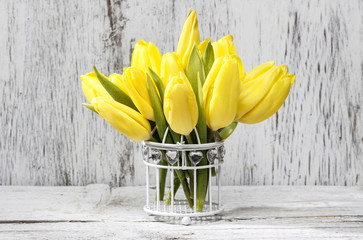 Small bouquet of yellow tulips on white wooden background