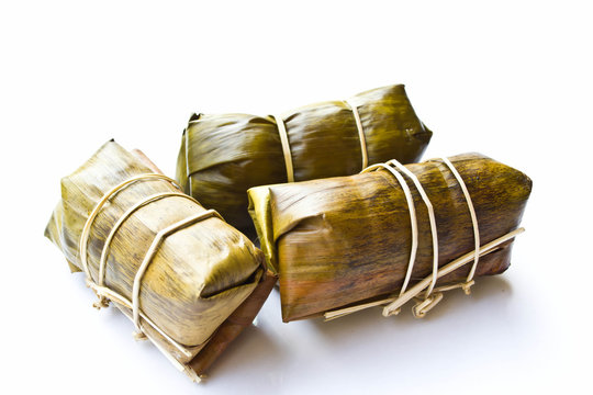 Sweets wrapped in banana leaves on a white background