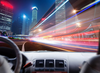 Driver's hands on a steering wheel of a car and night scene