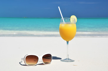 Orange juice and sunglasses on the beach. Exuma, Bahamas